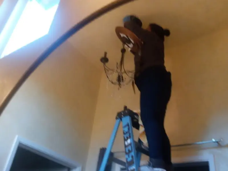 Electrician installing a chandelier in a Lewisville residence